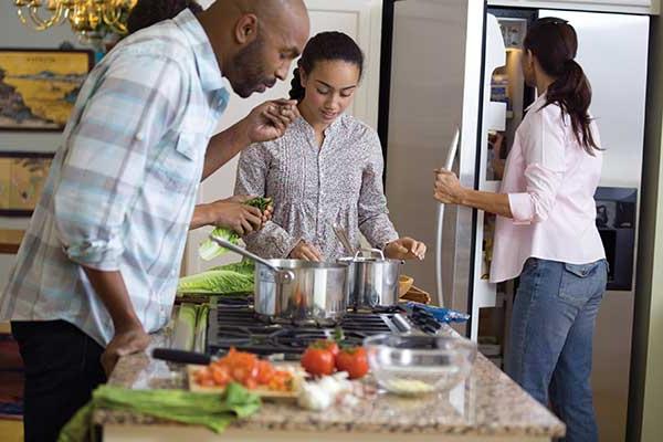 Family preparing meal around stove